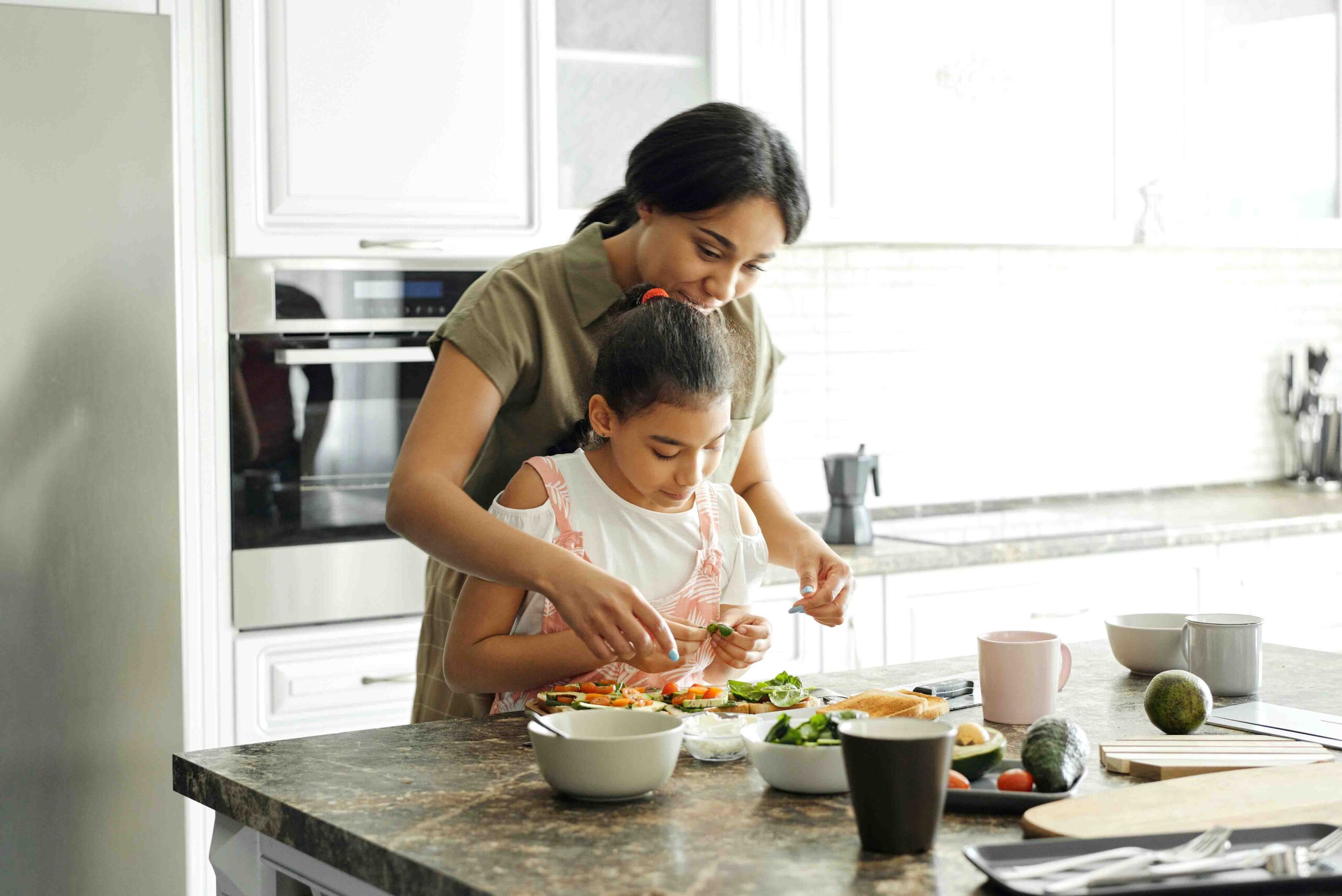 mother teaching little girl on how to prepare sandwich