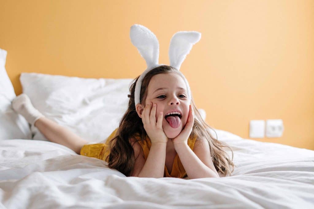 little girl on bed wearing bunny ears headband