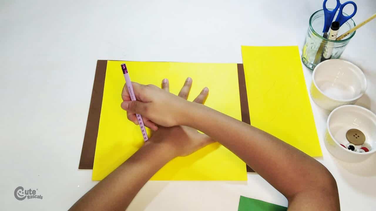 Draw the silhouette of the child's hand on the yellow paper