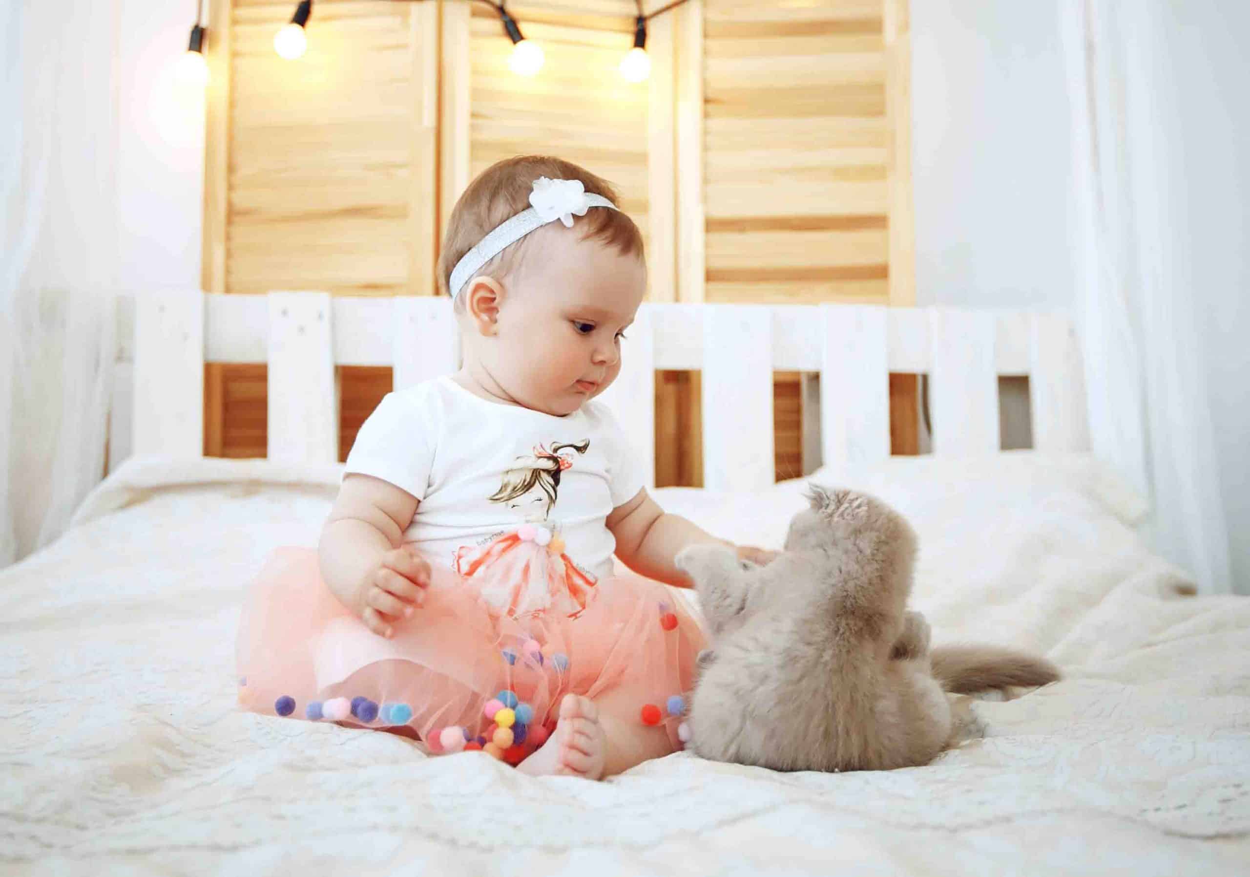 baby girl playing with cat on bed