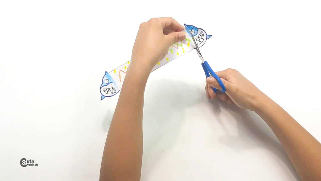 Make a small cut between the shark and the strip of paper